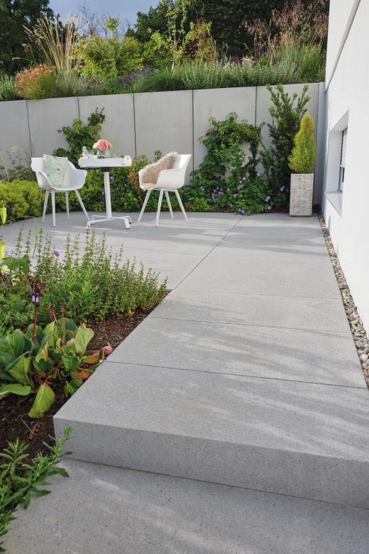 Zwei Stühle auf einer rundum bepflanzten Terrasse