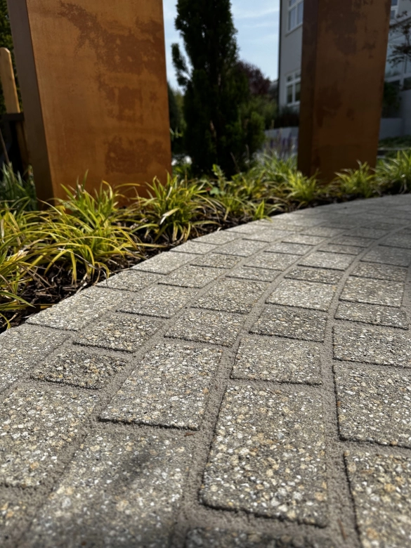 geschwungener Weg im Garten mit Sichtschutz Stelen in Cortenoptik