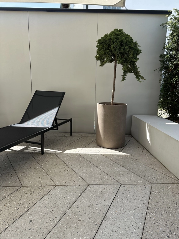 Terrassenplatten in Fischgrät-Optik mit einem Liegestuhl und einer Pflanze