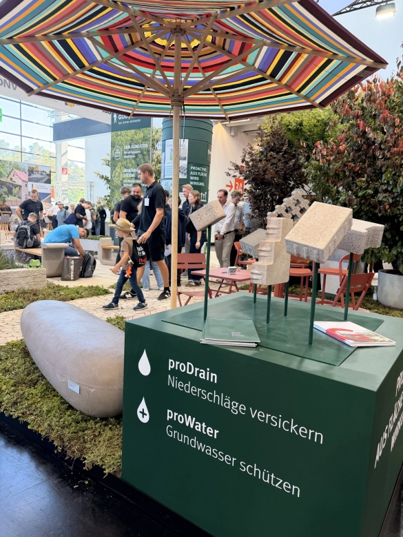 Besucher am Messestand unter bunten Sonnenschirmen