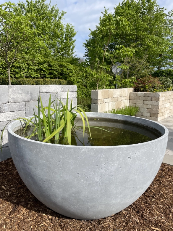Large stone-colored planter filled with water and plants