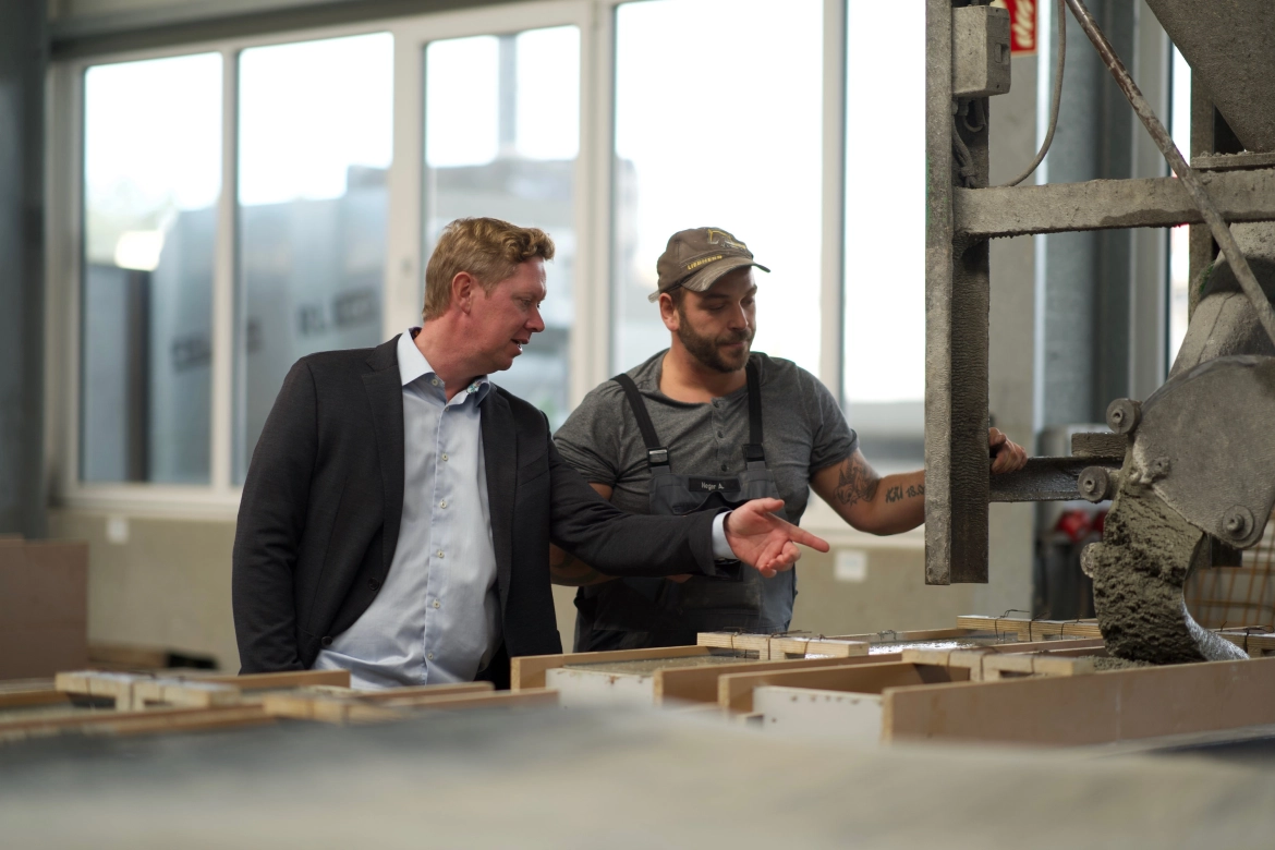 Two people stand in the concrete manufactory in front of formwork for special concrete components. They are discussing the formwork.