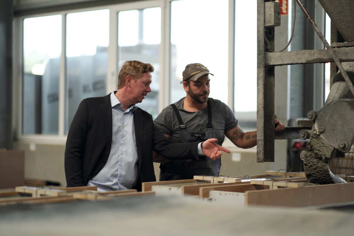 Zwei Personen stehen in der Beton-Manufaktur vor Schalungen für Sonderbauteile aus Beton. Sie besprechen die Schalungen.