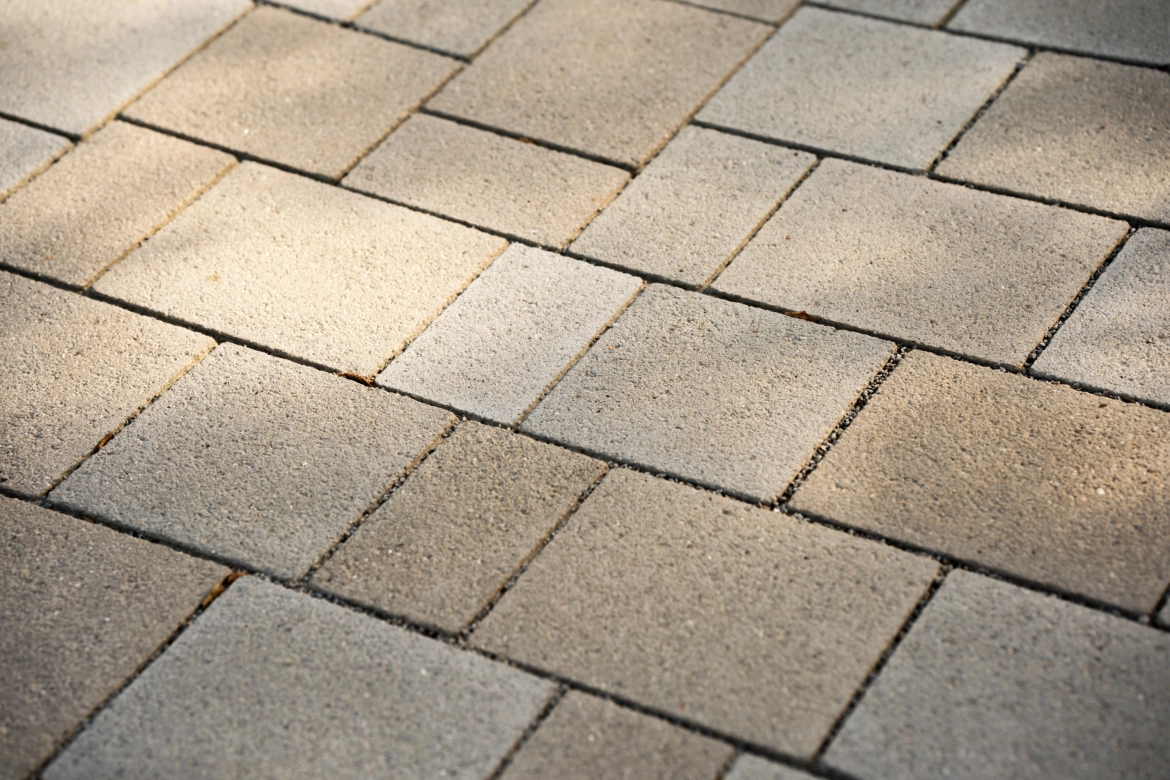 Ein gepflasterter Bereich, bestehend aus klimapositiven Betonsteinen, welcher im wilden Verband verlegt wurde. Der ökologische Flächenbelag hat eine edelstahlkugelgestrahlte, beige und kalkgraue Oberfläche