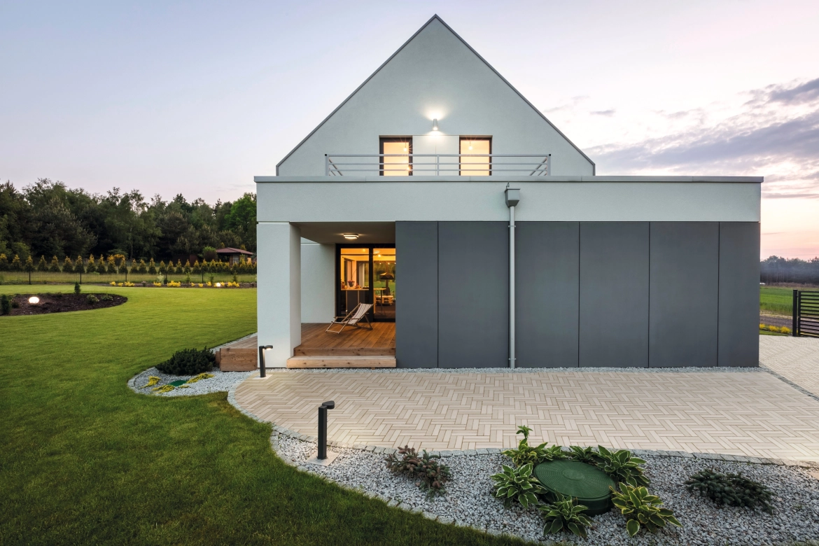 Haus mit Garage und Hofeinfahrt. Die Beleuchtung des Hauses ist angeschaltet.