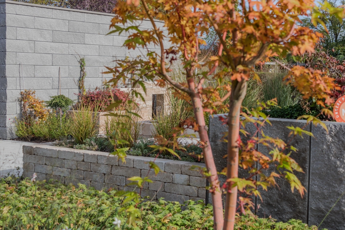 Herbstlich bepflanzter GODELMANN Ideen-Garten mit verschiedenen Pflasterflächen und Mauern 