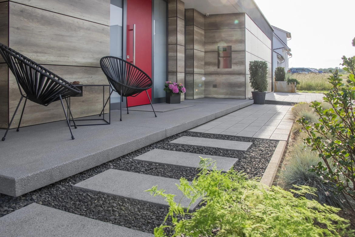 Hauseingang mit roter Tür und langem Podest aus Beton 