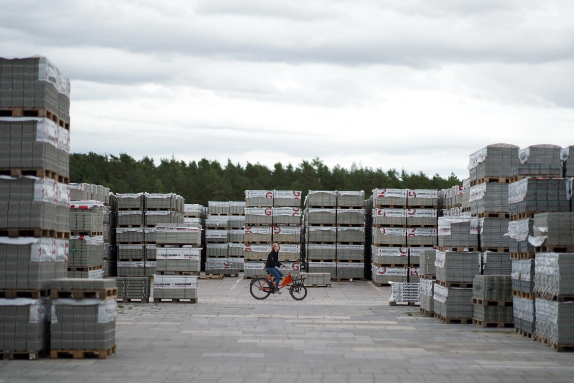  A cyclist rides across the factory premises between stacked stone packages on pallets.