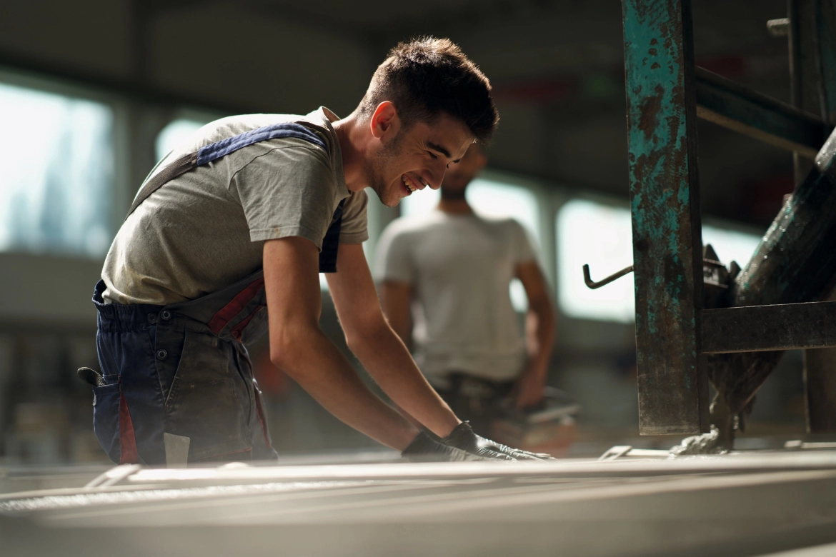 Young employee in the manufactory smoothing the concrete filled into the formwork with his hands.