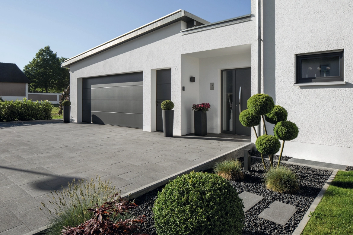 Zufahrt mit Garage zu einem modernen Haus mit dunklem Pflaster