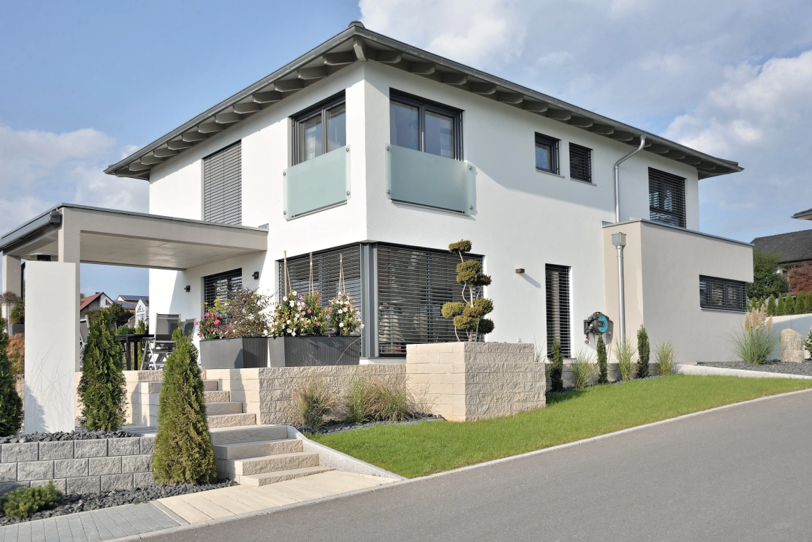 modernes Einfamilienhaus mit überdachter Terrasse, erhöhten und 
gmauerten Blumenbeeten und Treppenaufgang aus Betonsteinen in 
natürlichen Sandsteinfarben<br>