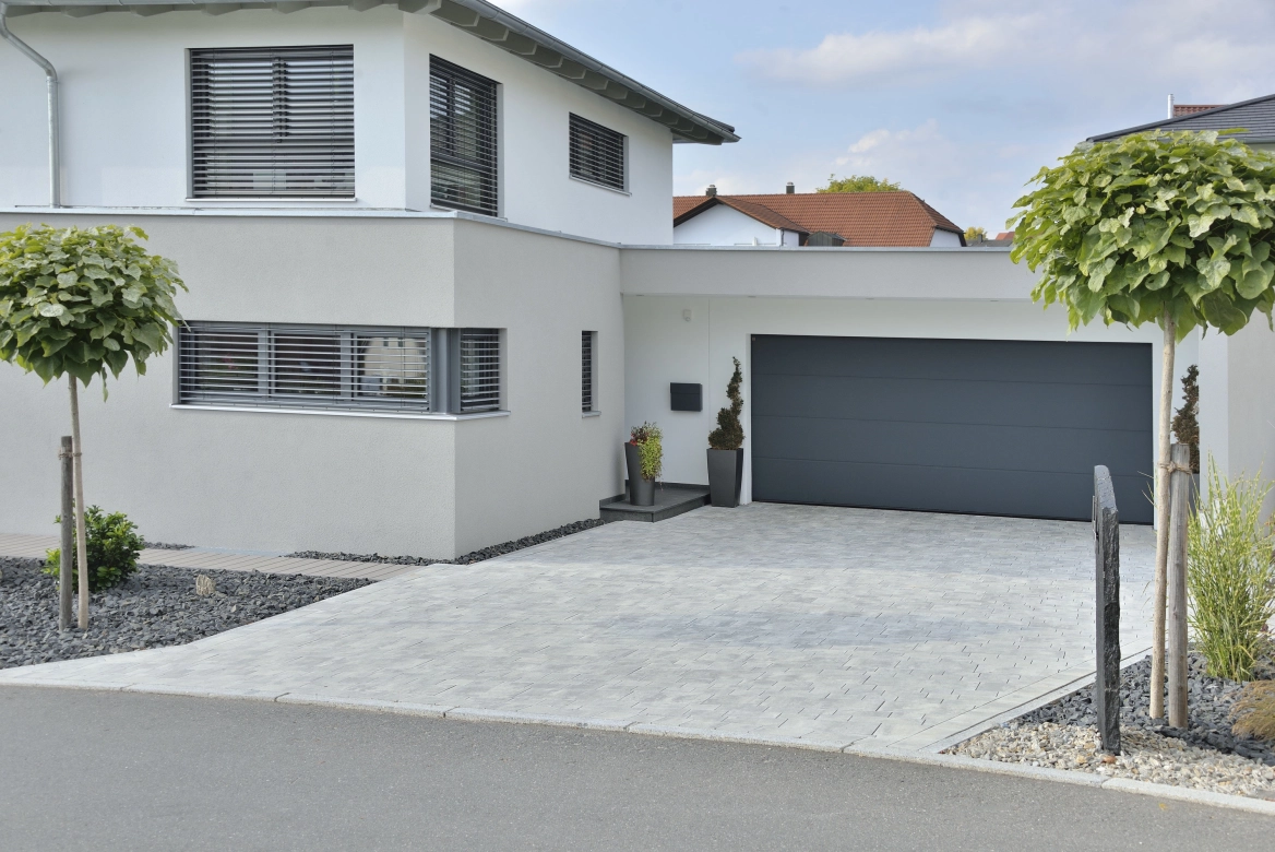 modernes Einfamilienhaus  mit nuancierten Pflastersteinen als Hofeinfahrt