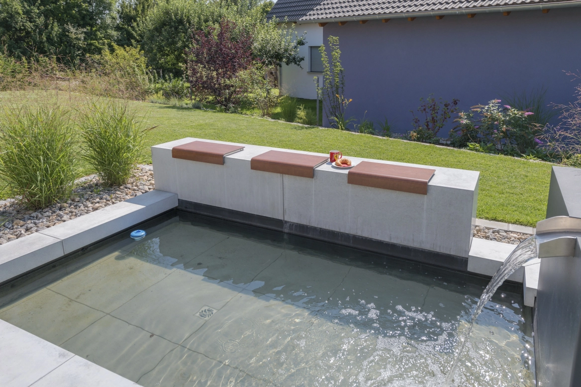 Wasserbecken integriert in der Terrasse mit einer Sitzbank aus Beton 