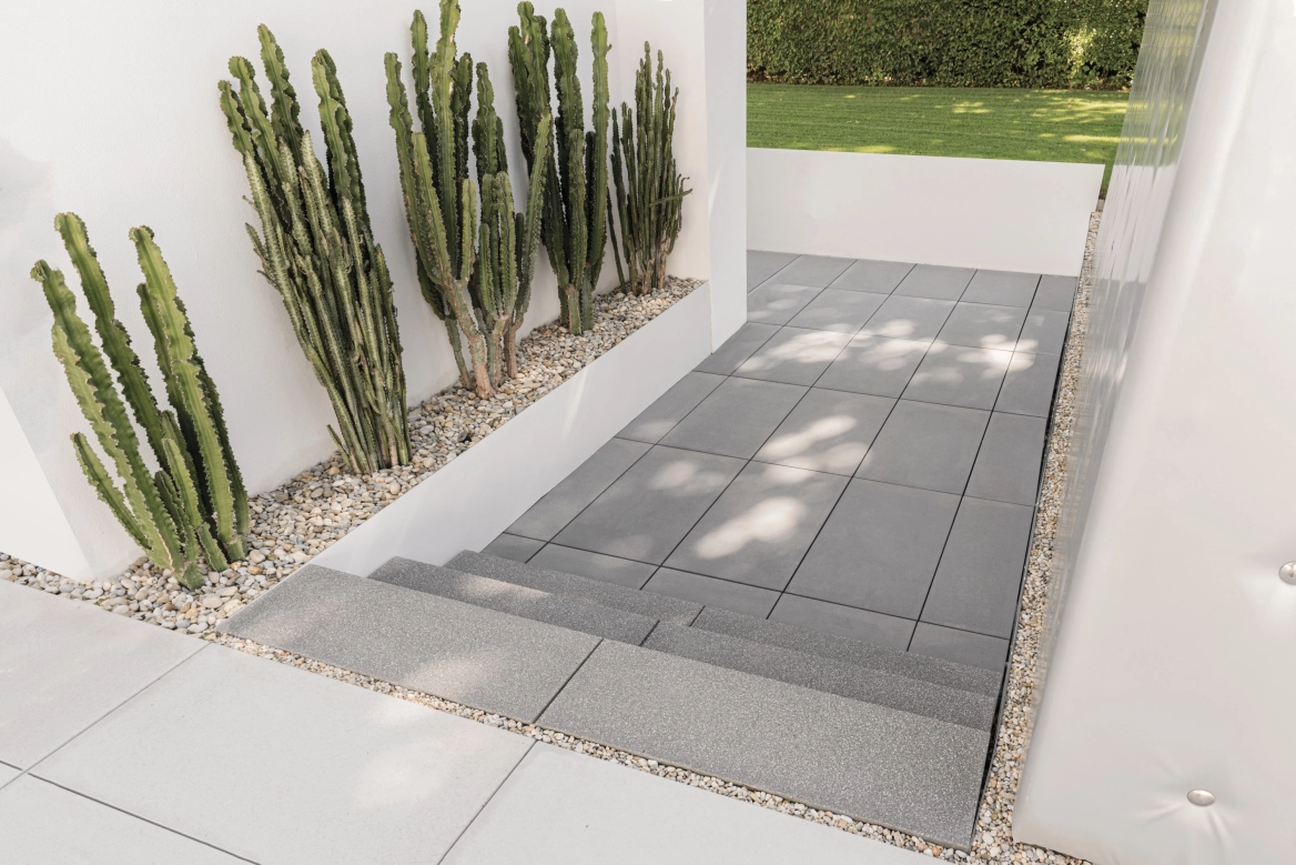 Pflaster Stufen aus Sichtbeton als Rundgang eines Privathauses mit Kakteen als Dekoration.
