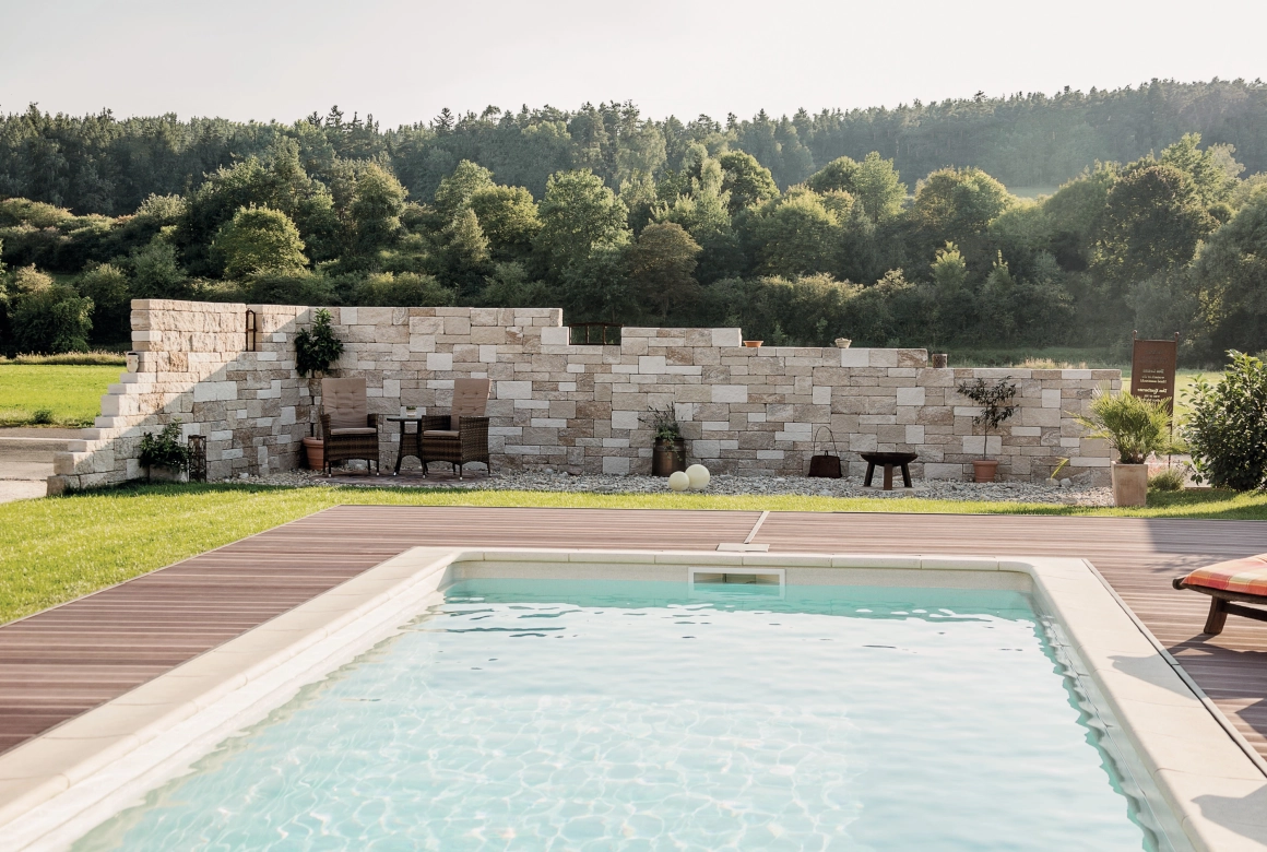 natürliche und abgetreppte Gartenmauer als Sichtschutz vor einem Pool