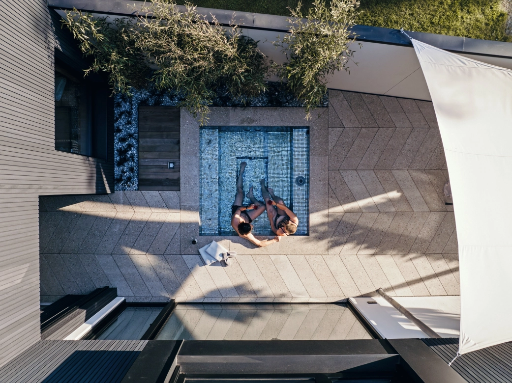 Kleiner Pool, umgeben von Terrassenplatten in Terrazzo-Optik, verlegt im stilvollen Fischgrätenverband