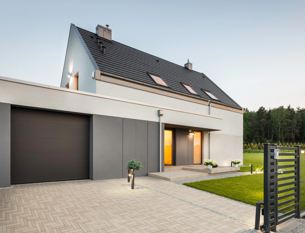 Haus mit Garage und Hofeinfahrt. Die Beleuchtung des Hauses ist angeschaltet.