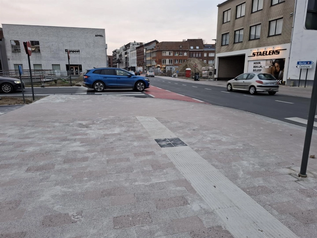 Blick auf eine Baustelle an einer asphaltierten Straße in Kortrijk. Die Gehwege wurden mit zeroC Pflastersteinen befestigt.
