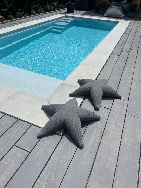 private Pool mit Terrassendielen in Holzoptik und Holzstruktur aus Beton in anthrazit