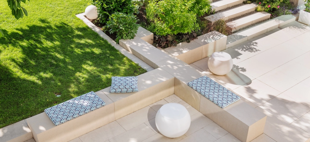 Privater moderner Garten mit sandsteinfarbener Terrasse und viel Grün