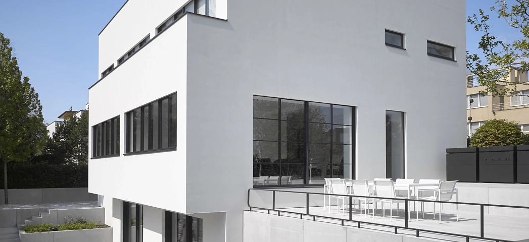 Moderne Villa hinter einem Pool mit weißen Terrassenplatten