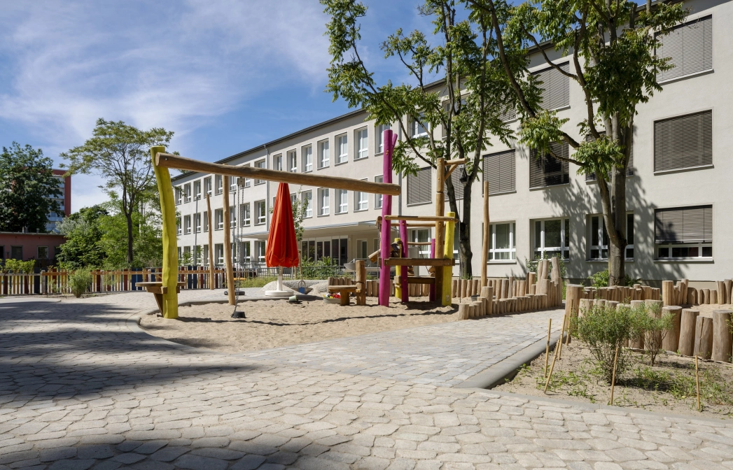 Außenbereich der Kita Wolkenschaf in Berlin mit naturnahen Spielgeräten und versickerungsfähigem GDM.BOLERO.