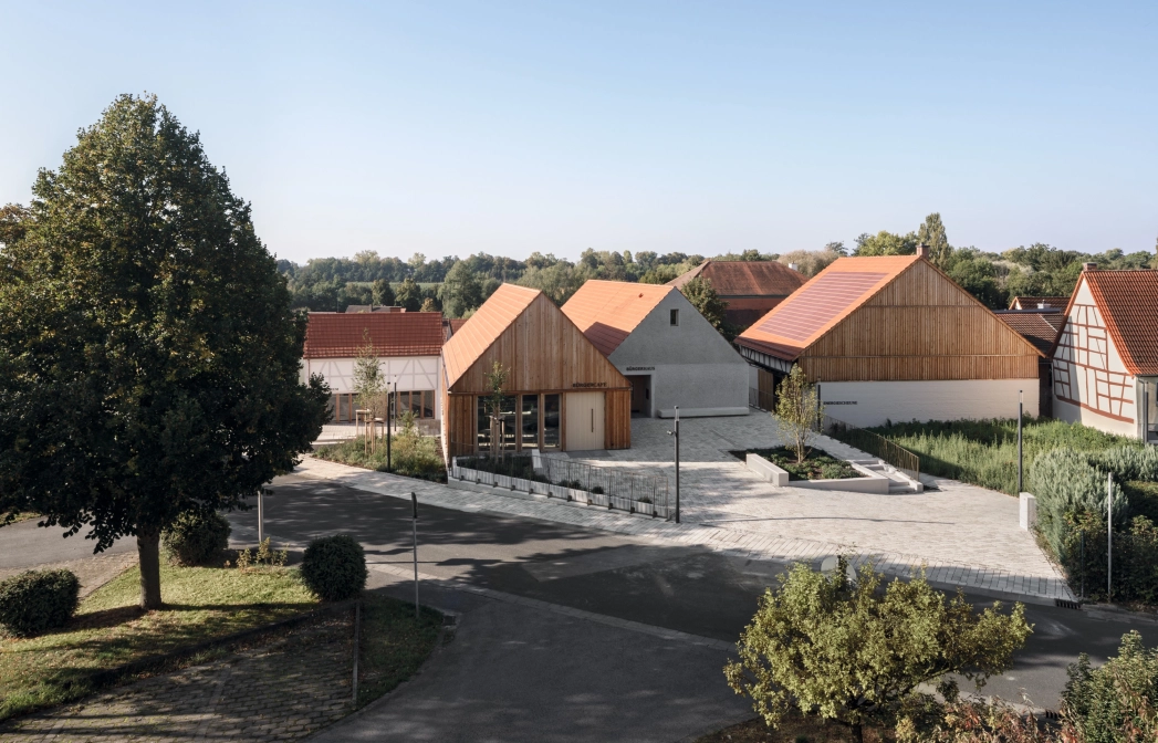 Wohngebiet mit modernen und traditionellen Häusern, baumgesäumten Straßen und klarem Himmel.