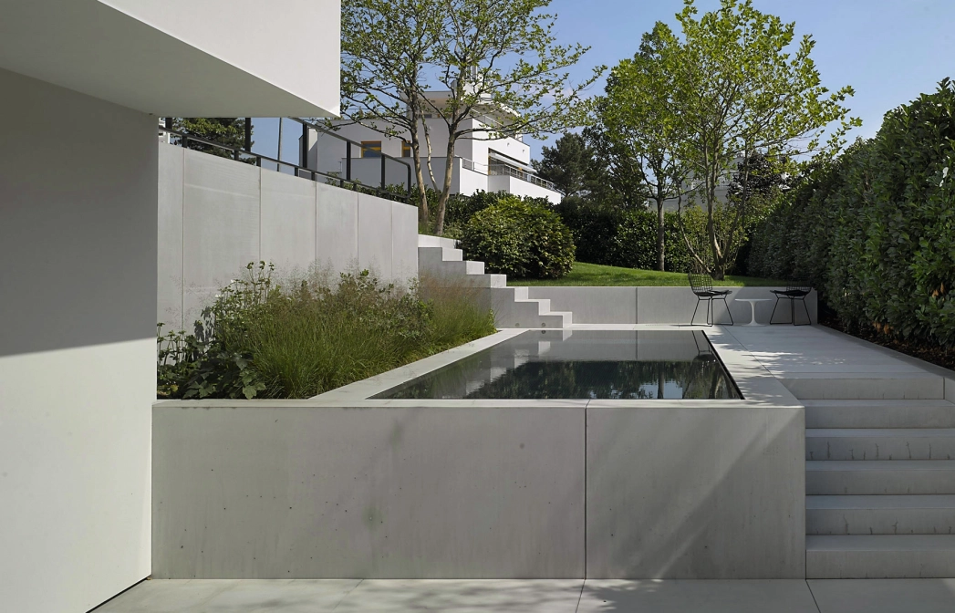 Garten einer modernen Villa mit weißen Treppenstufen, Terrassenplatten und Pool