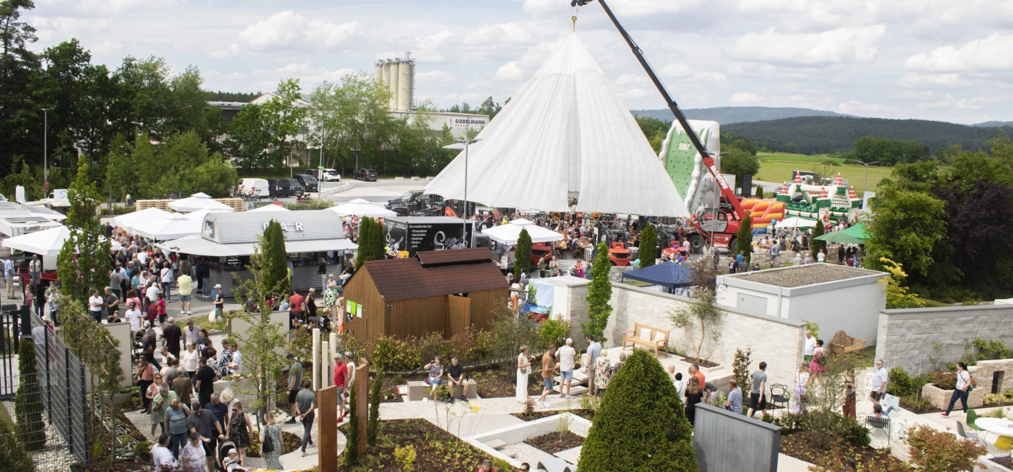 Eine Luftaufnahme zeigt das weitläufige Gelände des „Tag des Gartens“ mit zahlreichen weißen Zelten, Ausstellungsständen und einer großen Besucherzahl, umgeben von grüner Landschaft.