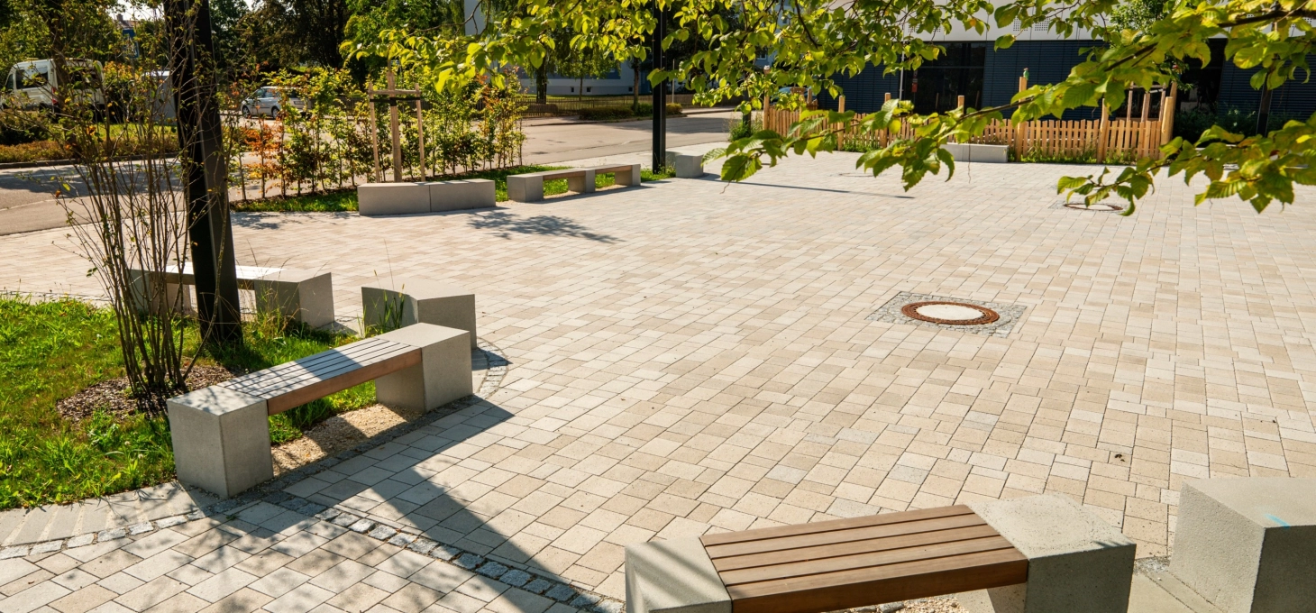 Blick auf den Pausenhof der Hans Kammerer Schule, mit Sitzbänken und Grünflächen am Rand