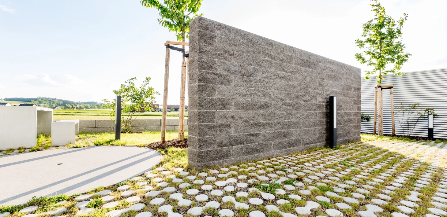 GDM.NOVO wallfreistehende Gartenmauer als Sichtschutz aus Betonsteinen aus Schiefer mit begrünten, ökologischen Rasensteinen.<br>