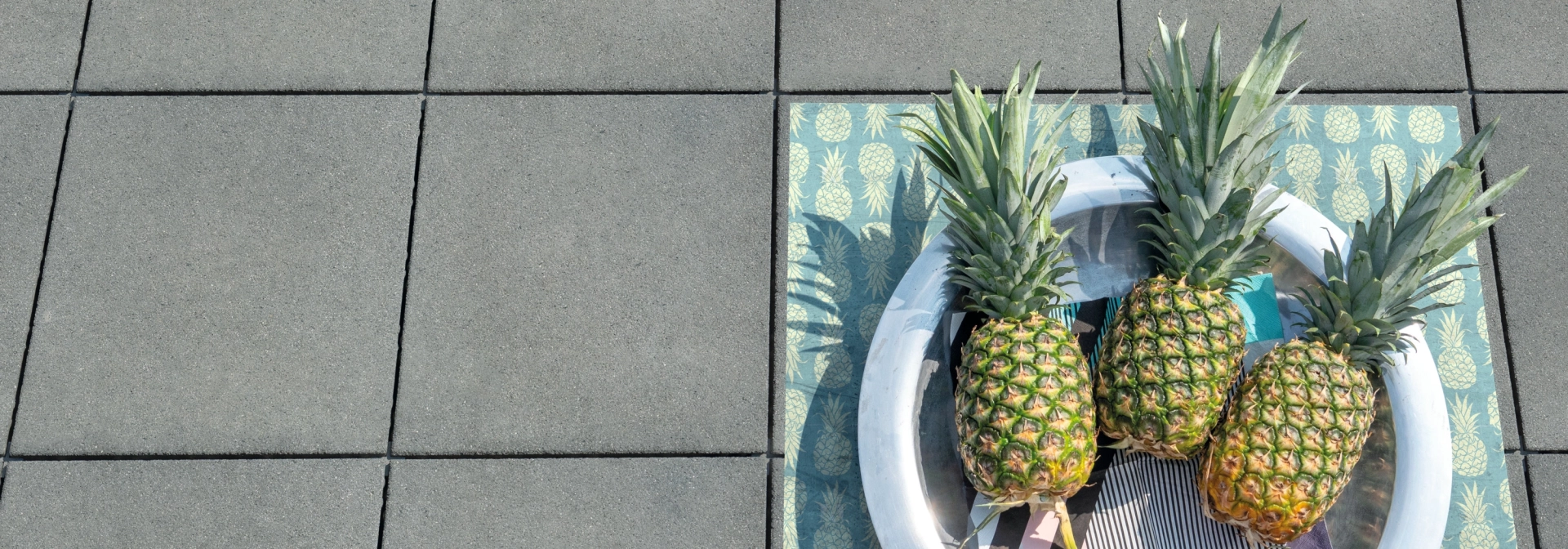 Drei Ananas liegen auf grauen Terrassenplatten