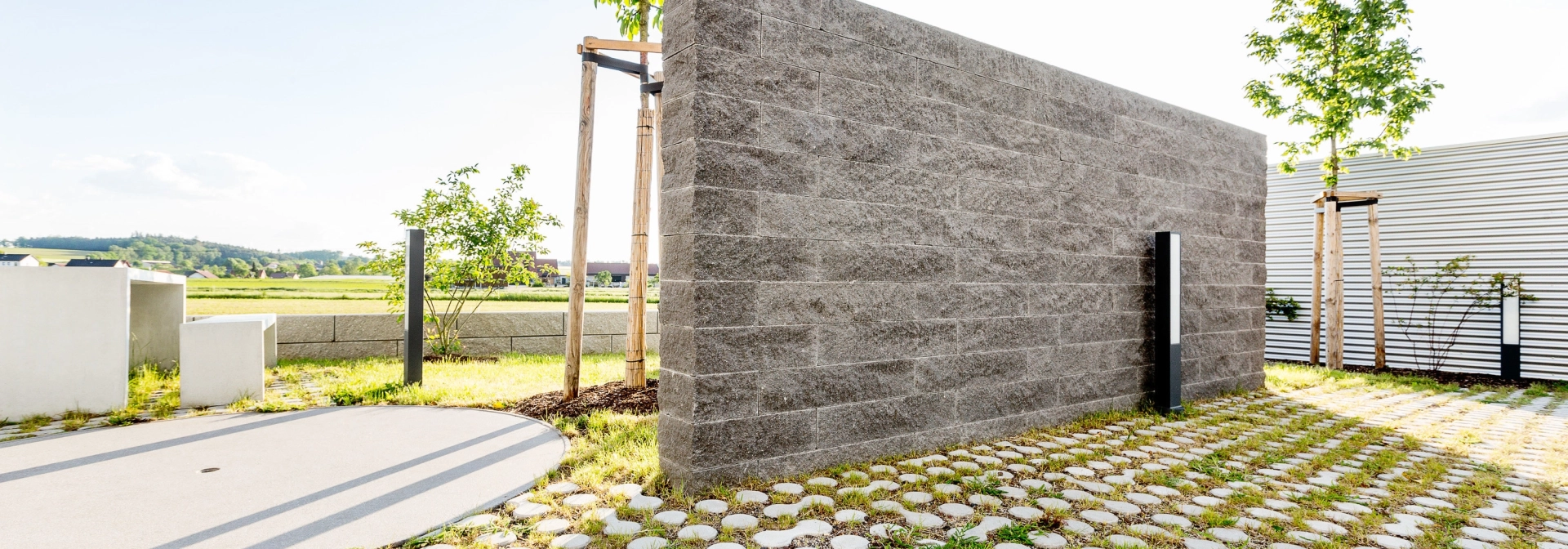 GDM.NOVO wallfreistehende Gartenmauer als Sichtschutz aus Betonsteinen aus Schiefer mit begrünten, ökologischen Rasensteinen.<br>