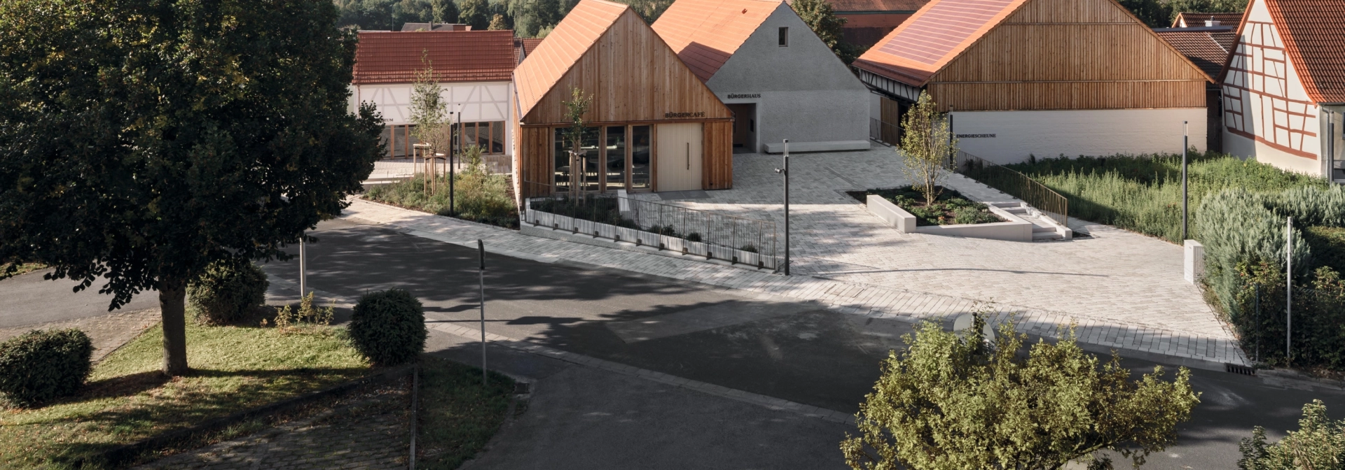 Wohngebiet mit modernen und traditionellen Häusern, baumgesäumten Straßen und klarem Himmel.