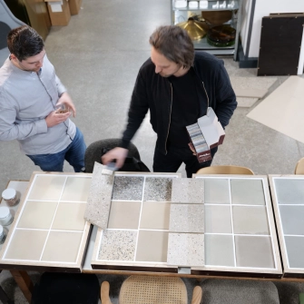Sebastian Herkner in Abstimmung mit GODELMANN bezüglich der Farben der Fliesen. Die Farbmuster liegen auf einem Tisch vor ihm.