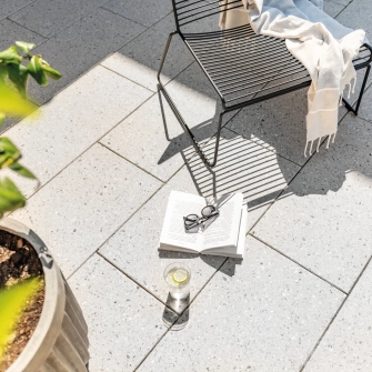 Terrasse mit Terrazzo Fliesen mit einem Metallstuhl und einem Buch auf dem Boden