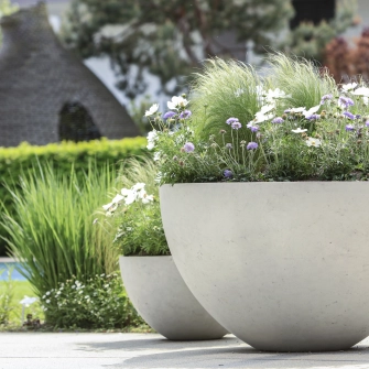 Planter unterschiedlicher Größen in einem grünen Garten