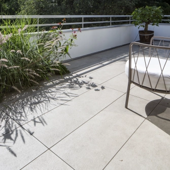 Dachterrasse mit beigen Betonfliesen mit Pflanzen und einem Stuhl