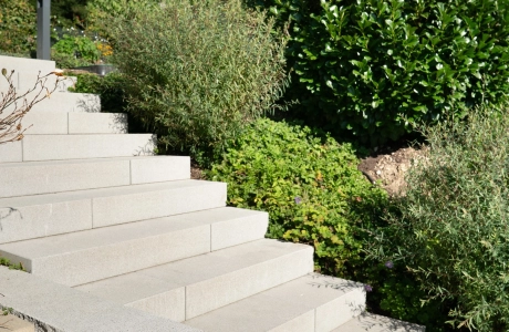 Helle GDM.NUEVA step, umgeben von dichter Gartenbegrünung; im Vordergrund verläuft die GDM.NOVO wal.