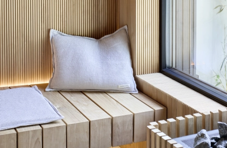Moderne Holzsauna mit Panoramafenster zum Außenbereich, gestaltet mit sandgrauen Terrazzo-Betonfliesen am Boden.