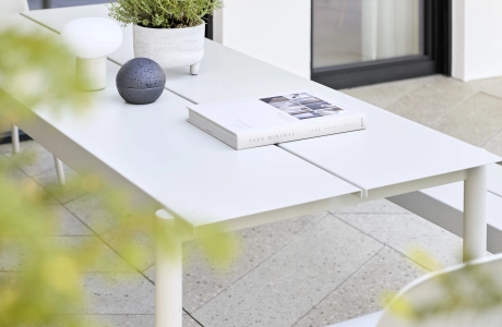 Terrasse mit sandgrauen Terrazzo-Designfliesen in eleganter Fischgrät-Optik mit modernen weißen Tisch