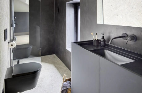 Stilvolles Badezimmer mit anthrazitfarbenen schwarzen Akzenten und Terrazzo-Betonfliesen auf dem Boden