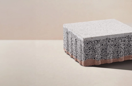 Ein Pflasterstein mit dreischichtigem Aufbau vor einem beigefarbenen Hintergrund