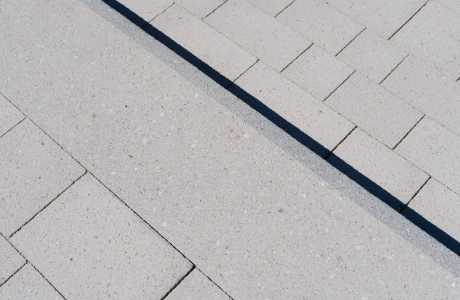 Nahaufnahme von einer Stufe mit granitfarbenen Betonpflastersteinen und einem schwarzen Kontraststreifen an der Trittkante.