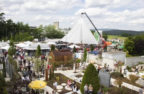 Eine Luftaufnahme zeigt das weitläufige Gelände des „Tag des Gartens“ mit zahlreichen weißen Zelten, Ausstellungsständen und einer großen Besucherzahl, umgeben von grüner Landschaft.