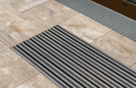 Metallfußmatte in muschelkalkfarbene Betonsteine, eingelassen.