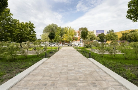 Gehweg, mit dem muschelkalkfarbenem GDM.KLIMASTEIN, welcher in Richtung Stadt führt. Der Weg wird durch den GDM.MAXI block begrenzt. Daneben sind Grünflächen mit Bäumen und Sträuchern