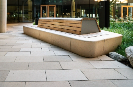 GDM.MASSIMO seat mit Holzauflage. Davor ist der GDM.SCENIC individual verlegt. Dahinter ist ein begrüntes Beet mit schwarzer Stele.