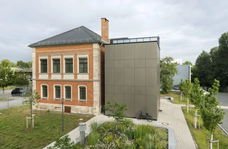 Gebäudeseite der RekoSUN Stadtentwässerung Nürnberg mit Wegen und Platzflächen aus GDM.ACENTRO stone in Granit Perlmut-Gelb.