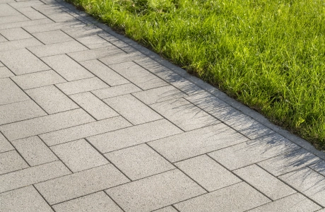 Nahaufnahme eines, mit basalt- und granitfarbenem GDM.SCENIC individual gepflasterten Weges. Rechts daneben befindet sich eine Rasenfläche.